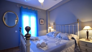 A bedroom with a bed, two bedside tables, a mirror, and a ceiling fan. - LA MARINA 3 21 - Two Bedroom Apartment, Sleeps 5 (Punta del moral)