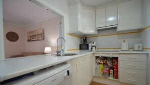 A compact kitchen with white cabinets, a Bosch dishwasher, a microwave, and a coffee maker.