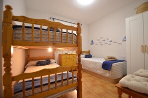 Une chambre avec un lit superposé, un lit simple, une commode et une armoire.