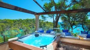 A hot tub with a wooden frame, blue cushions, and a towel. - Stunning Seafront Villa in the Mondragó National Park, Amazing Views & Direct Access to the Beach! (Cala Mondrago)