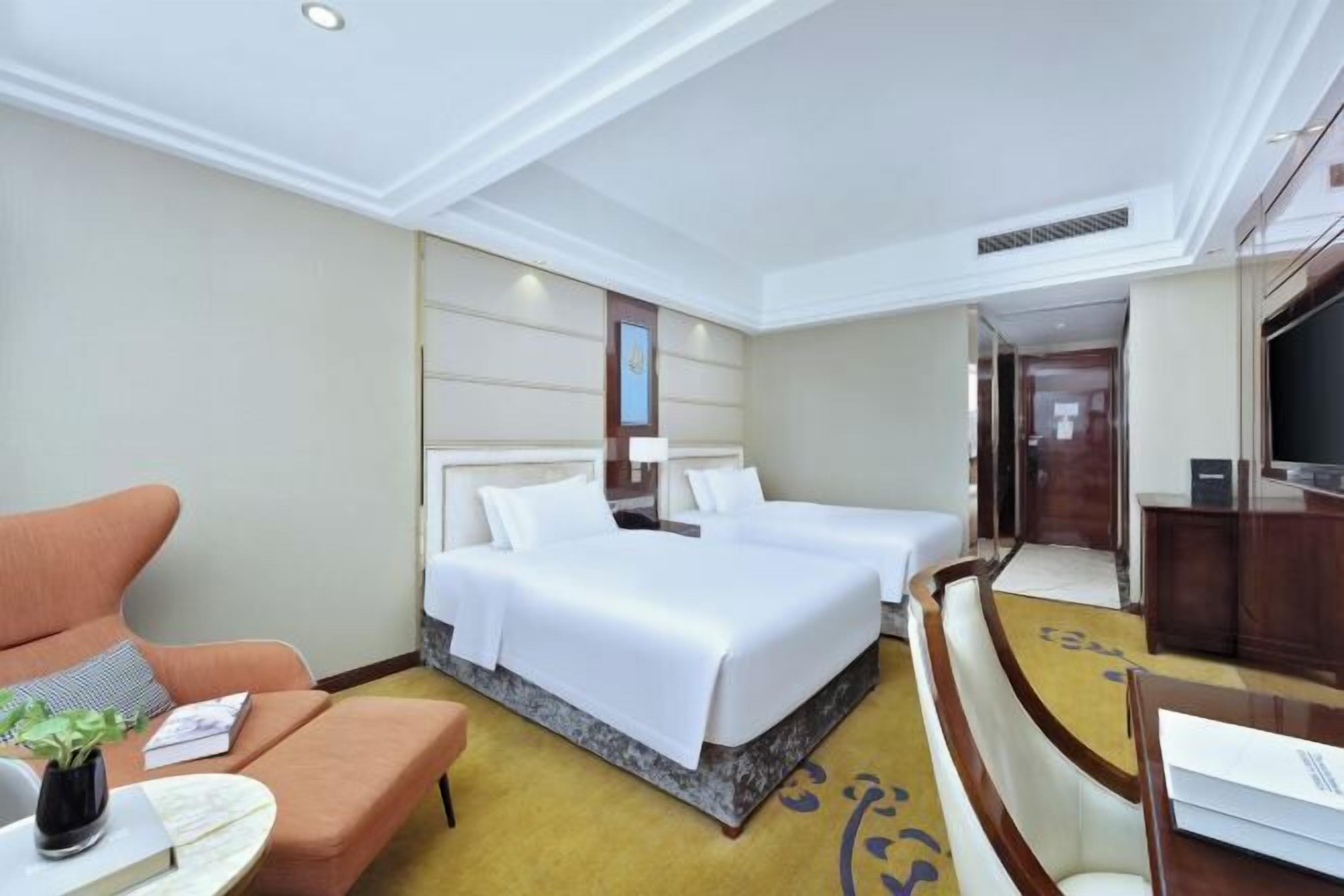 A hotel room with a bed, a sofa, a desk, and a TV.