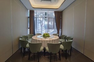 A conference room with a round table, eight chairs, and a floral centerpiece.