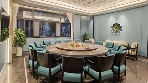 Una sala de conferencias moderna con una mesa redonda, sillas color aguamarina y un centro de mesa floral decorativo.