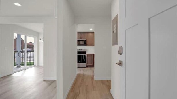 Un intérieur moderne comprenant un espace cuisine, un plancher en bois et une porte blanche.