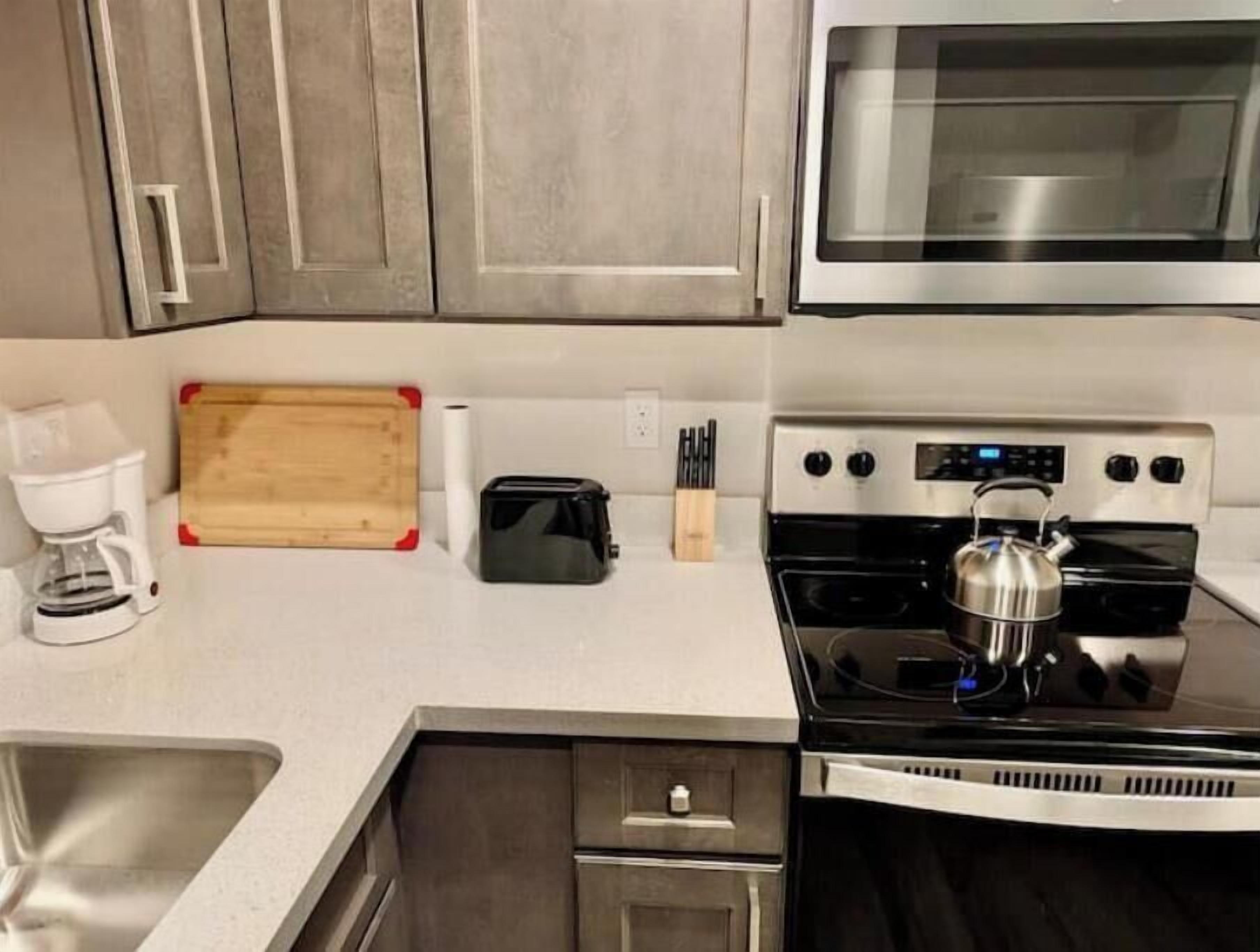 Une cuisine équipée d’appareils électroménagers en acier inoxydable, d’une machine à café, d’un grille-pain et d’une planche à découper en bois.
