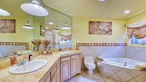 A bathroom with two sinks, a toilet, and a bathtub. There are ceiling lights and artwork on the walls. - The Rhododendron House is a spacious cottage in Waynesville, NC. It is ideal for families traveling with younger and older children and longer term stays. This open floor plan, 1000sq foot cottage is a stand alone building and has ample space to spre (Waynesville)
