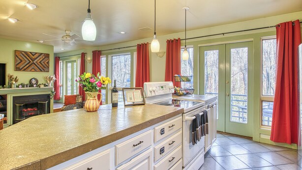 A kitchen with a large island, a built-in oven, and a dining area. - The Rhododendron House is a spacious cottage in Waynesville, NC. It is ideal for families traveling with younger and older children and longer term stays. This open floor plan, 1000sq foot cottage is a stand alone building and has ample space to spre (Waynesville)