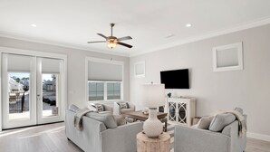 A spacious living room with a grey sofa set, a wooden coffee table, and a ceiling fan. - Pool, Walk To Beach & Restaurants, Firepit, 4BR + Bunks, Summer Salt Amenities (Orange Beach)