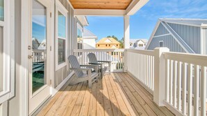A wooden deck with a white railing, two Adirondack chairs, and a small table. - Pool, Walk To Beach & Restaurants, Firepit, 4BR + Bunks, Summer Salt Amenities (Orange Beach)