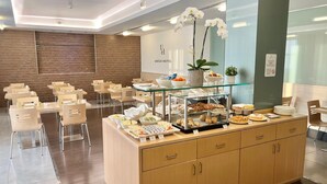 Un hall d’hôtel moderne avec un espace buffet proposant divers plats et une vitrine réfrigérée.