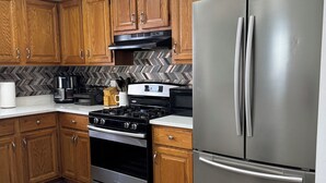 Une cuisine moderne avec des meubles en bois, des appareils électroménagers en acier inoxydable et un dosseret de carrelage disposé en motif chevron.