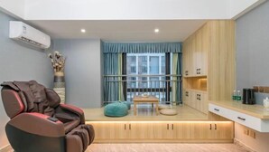 A modern living room with a massage chair, a small table, and a view of the city through large windows. - Jinfan City Hotel (Fuzhou)