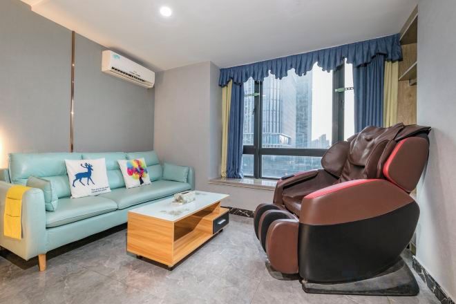 A room with a sofa, massage chair, and a coffee table.
