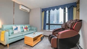 A room with a sofa, massage chair, and a coffee table.