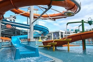 Zona de parque acuático con toboganes y piscinas en la cubierta de un crucero.