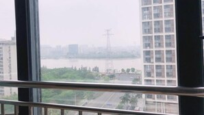 A view from a high-rise window overlooking a river, with buildings and a power line in the distance. - Jinfan City Hotel (Fuzhou)