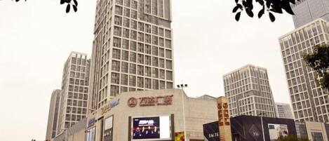 A cityscape with tall buildings, a large digital billboard, and a busy street.