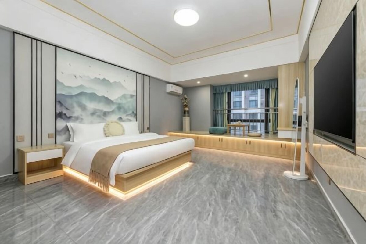 Une chambre moderne avec un grand lit, une télévision et une vue sur la ville.