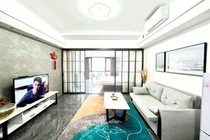 Een moderne woonkamer met een flatscreen televisie, een bank, een salontafel en een kamerkleed met een patroon.