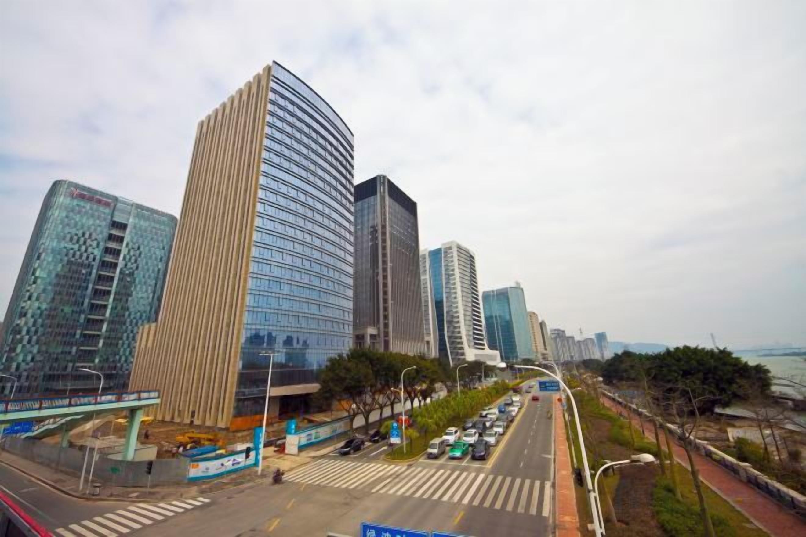 A cityscape with modern high-rise buildings, a road with vehicles, and a pedestrian walkway.