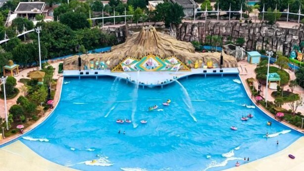 A large swimming pool with multiple water slides and a central island with a thatched roof. - Jinfan City Hotel (Fuzhou)