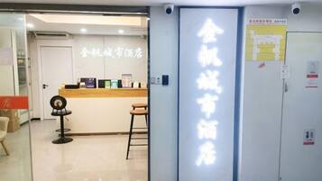 A hotel reception area with a reception desk, chairs, and a glass partition.