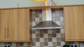 Eine Küche mit Holzausstattung, einem Gasherd und einer karierten Spritzschutzwand.