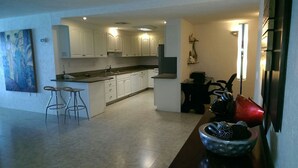 A modern kitchen with white cabinets, a central island with stools, and a decorative bowl on the counter. - 4/4.5 Condo Oceanfront Cozumel Downtown AC WiFi Security (Cozumel)