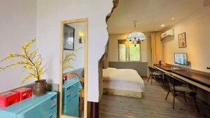 Hotelkamer met een bed, bureau en stoel, een spiegel en een kleine plant.