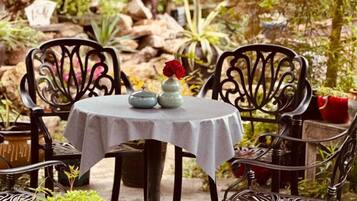 A round table with a white tablecloth, two decorative vases, and red flowers.