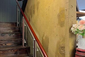 Uma escada de madeira com corrimão de metal que leva a uma parede amarela.
