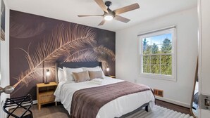 A bedroom with a bed, a ceiling fan, a nightstand, a lamp, a window, and a view of trees. - Spacious 8 beds LUX convenient Home close to DC (Bethesda)