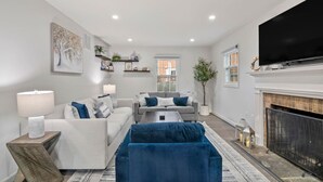 A modern living room with a fireplace, a television, and a large window. - Spacious 8 beds LUX convenient Home close to DC (Bethesda)