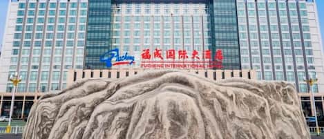 Un edificio grande con un letrero llamativo del Hotel Fucheng International.