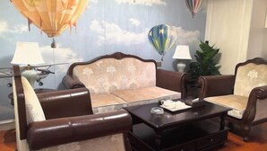 A room with a sofa, two armchairs, a coffee table, and a wall mural of hot air balloons. - Fucheng International Hotel (Sanhe)