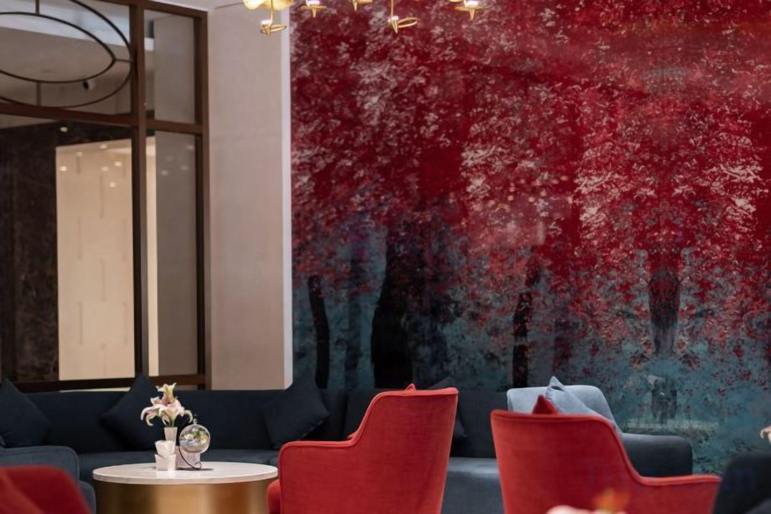A modern interior with a red abstract wall, round tables, and red and black seating.