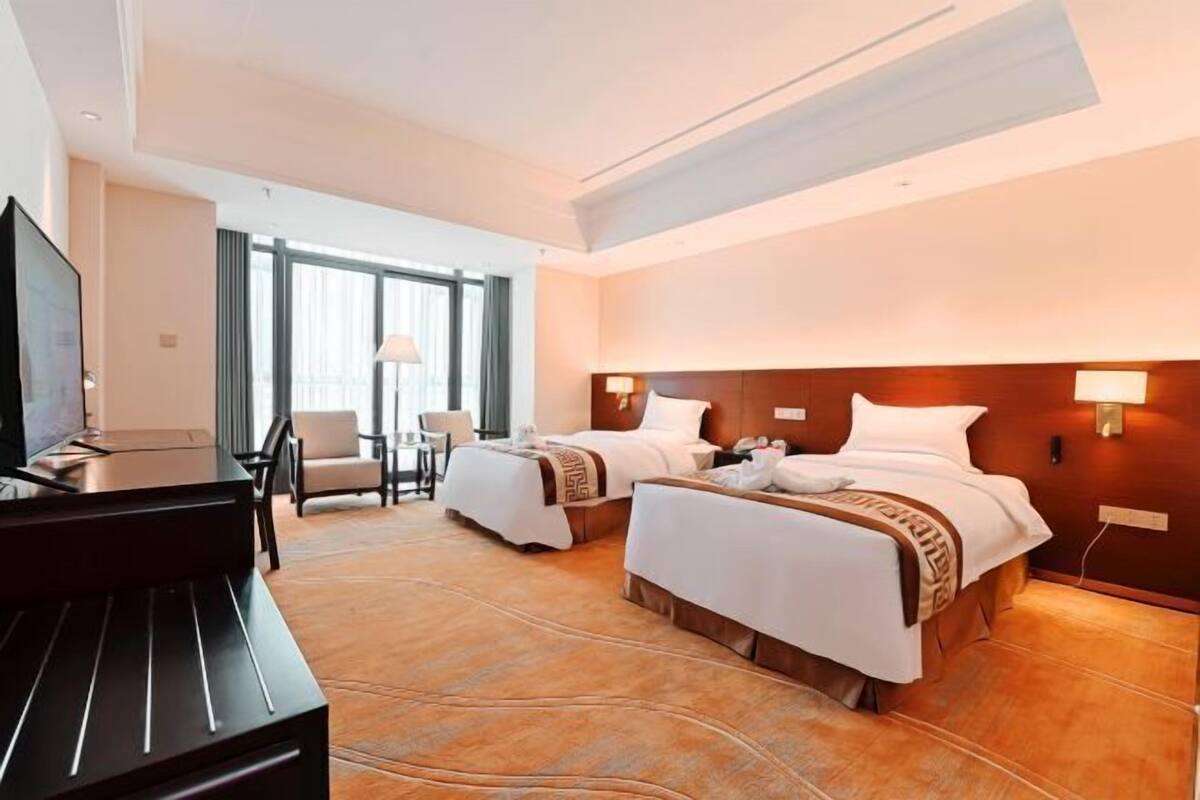 Une chambre d’hôtel avec deux lits, une télévision, un bureau et une chaise.
