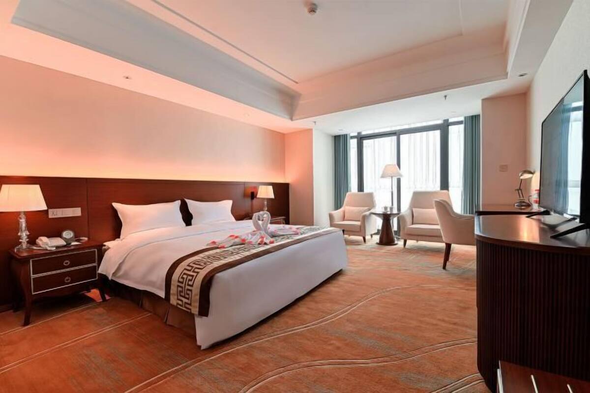 Une chambre d’hôtel avec un grand lit, un bureau, une chaise et un téléviseur.