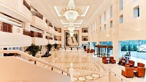 A spacious lobby with a grand chandelier, multiple floors, and a central seating area. - Fucheng International Hotel (Sanhe)