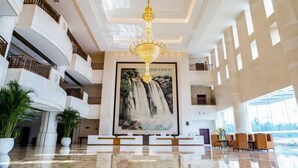 A spacious lobby with a high ceiling, a large chandelier, and a waterfall mural. - Fucheng International Hotel (Sanhe)