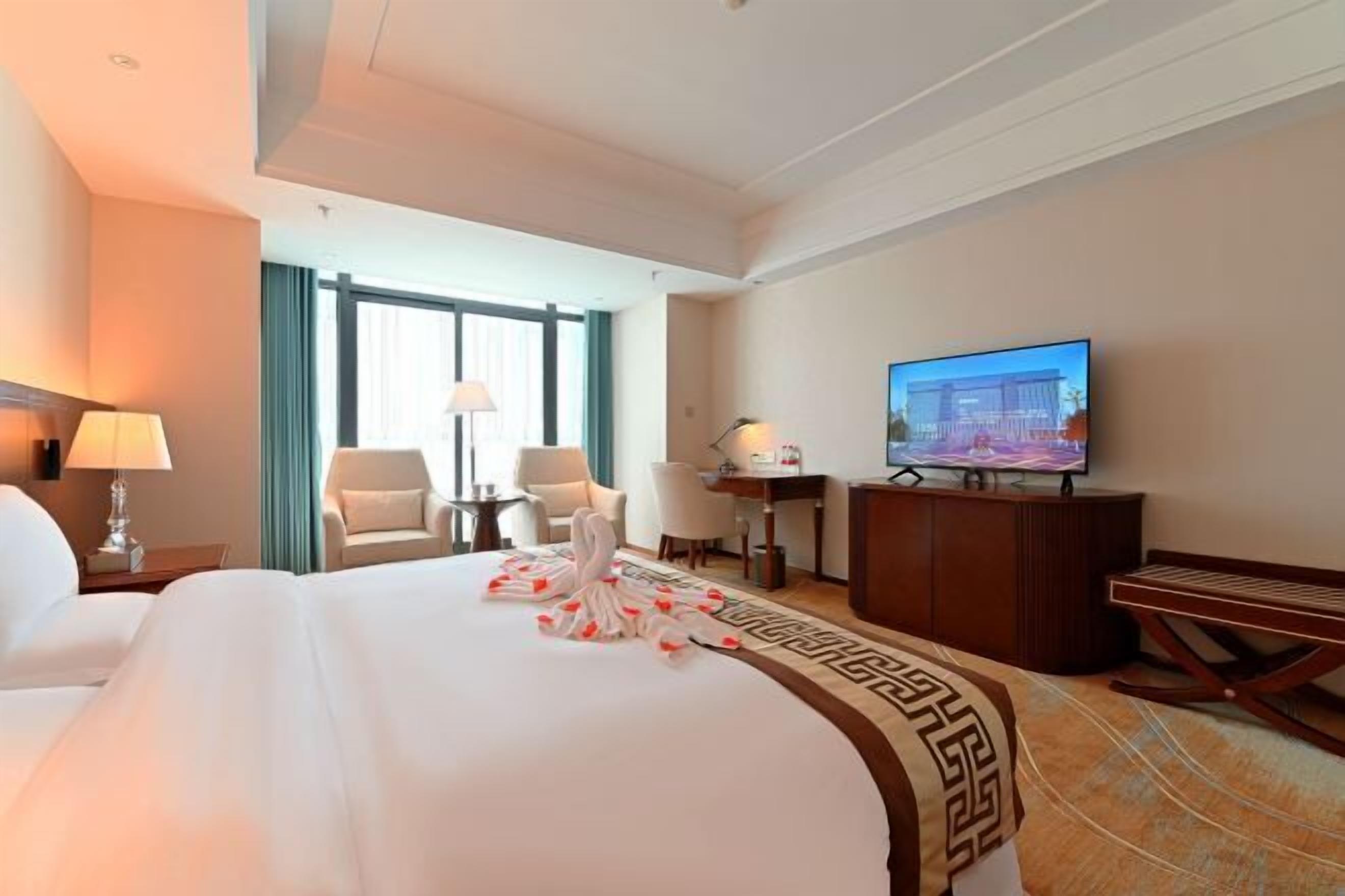 Una habitación de hotel con una cama grande, televisión, escritorio y silla.