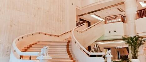 A multi-level interior with a central staircase, railings, and a potted plant.