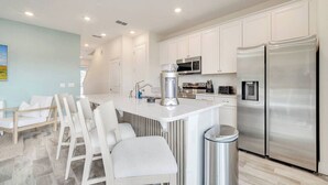 A modern kitchen with white cabinets, stainless steel appliances, and a central island with seating.