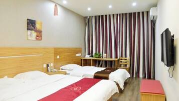 A hotel room with two beds, a desk, a chair, a television, and a striped curtain.