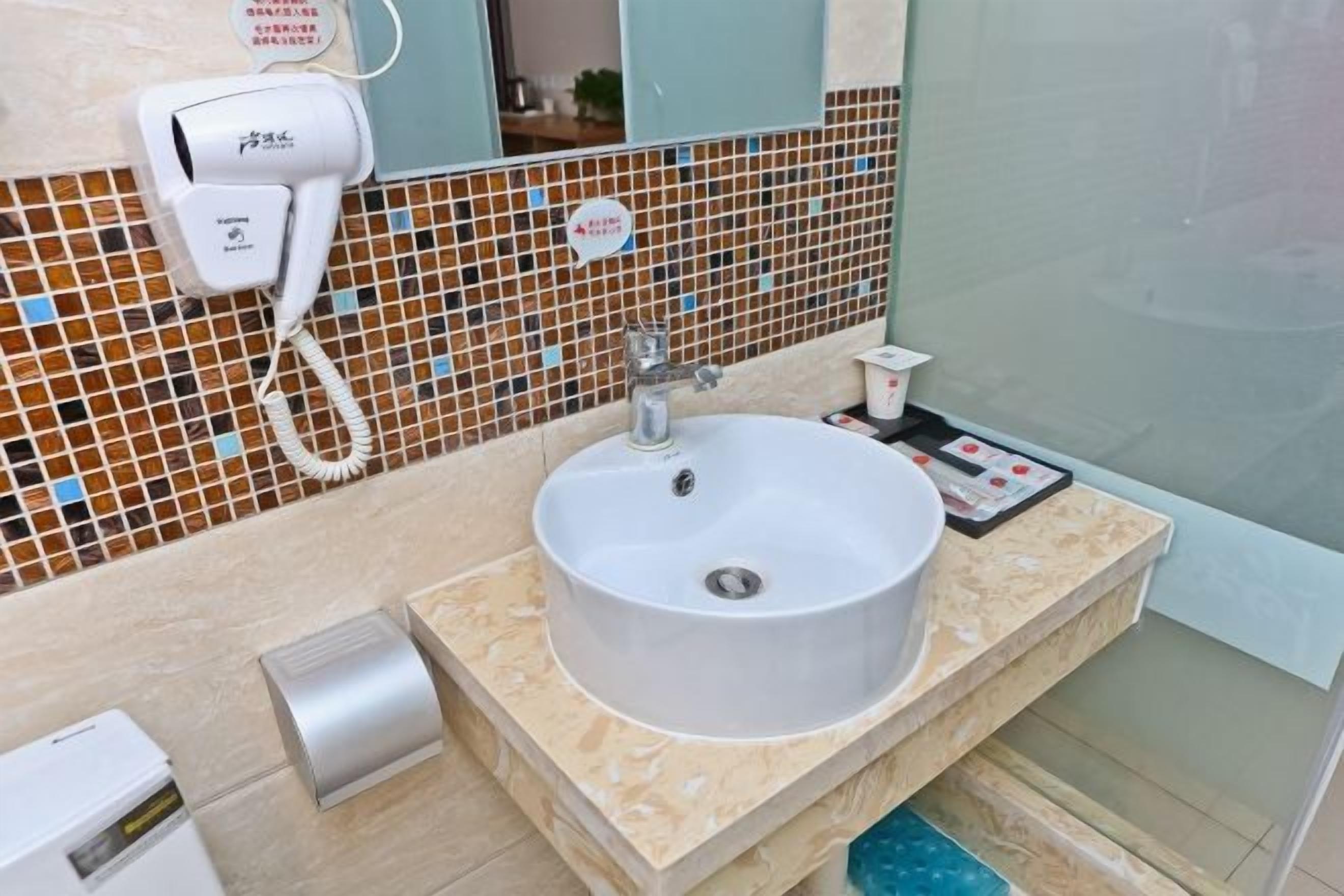 A bathroom with a white sink, a hairdryer, and a tiled backsplash.