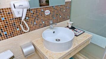 A bathroom with a white sink, a hairdryer, and a tiled backsplash.