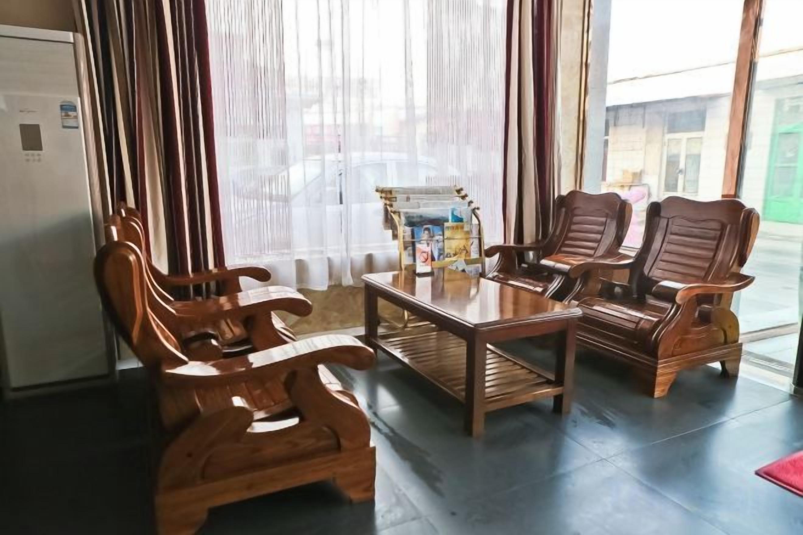 A room with a wooden table and four chairs, a refrigerator, and a window with curtains.