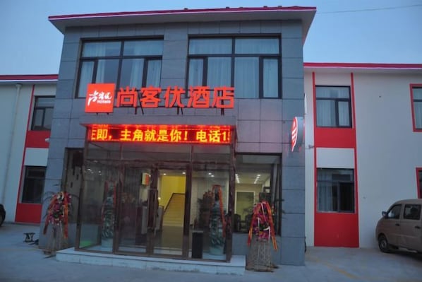 A hotel with a prominent sign, a glass facade, and a red and white color scheme.