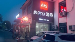 Un hôtel avec une enseigne indiquant qu’il est accueillant pour les clients, un numéro de téléphone et un parking où sont garées des voitures.