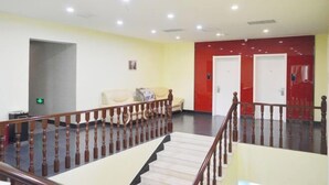 Un hall d’hôtel avec un escalier, un canapé et des portes rouges.